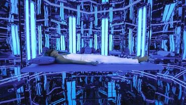 A person laying on the ground in front of blue lights.